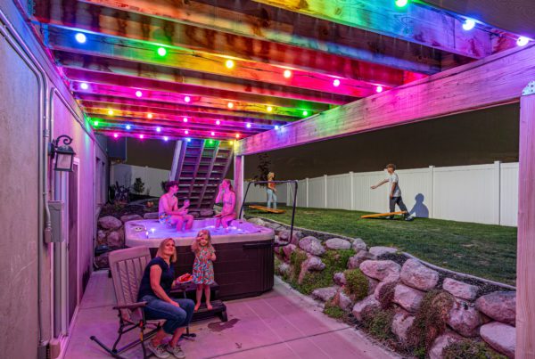 Trimlight Can Enhance Your Outdoor Space. In this photo you see the Trimlight globe lights over a hot tub. The lights are a rainbow of pink, yellow, blue and purble.